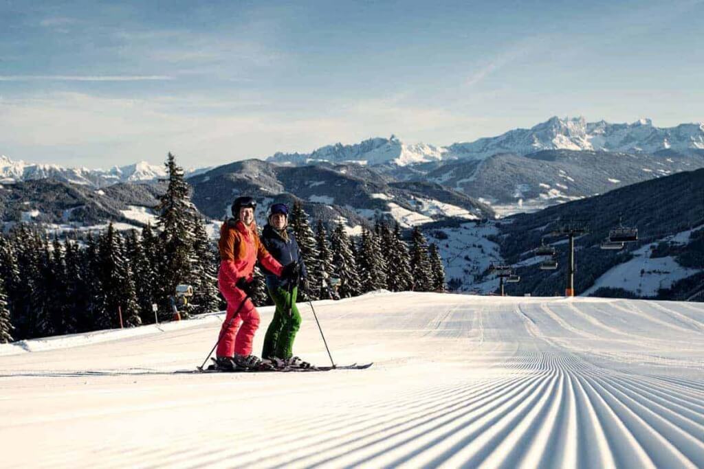 Paar beim Skifahren auf präparierter Piste mit Bergpanorama im Hochkönig.