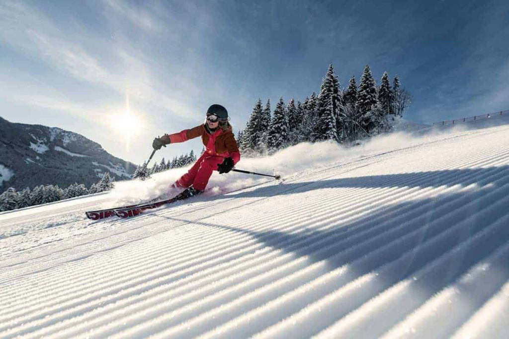 Skifahrer carve über die unberührte Piste im Hochkönig-Gebiet bei sonnigem Wetter.