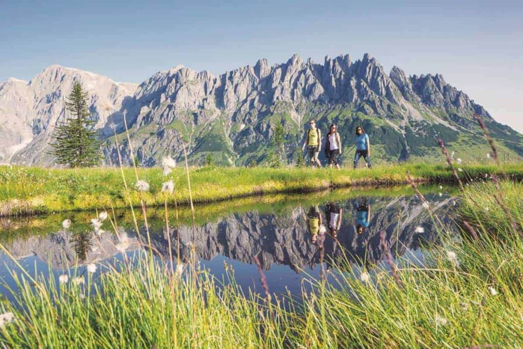 Wanderer am Ufer eines klaren Sees, im Hintergrund die majestätischen Hochkönig-Berge.