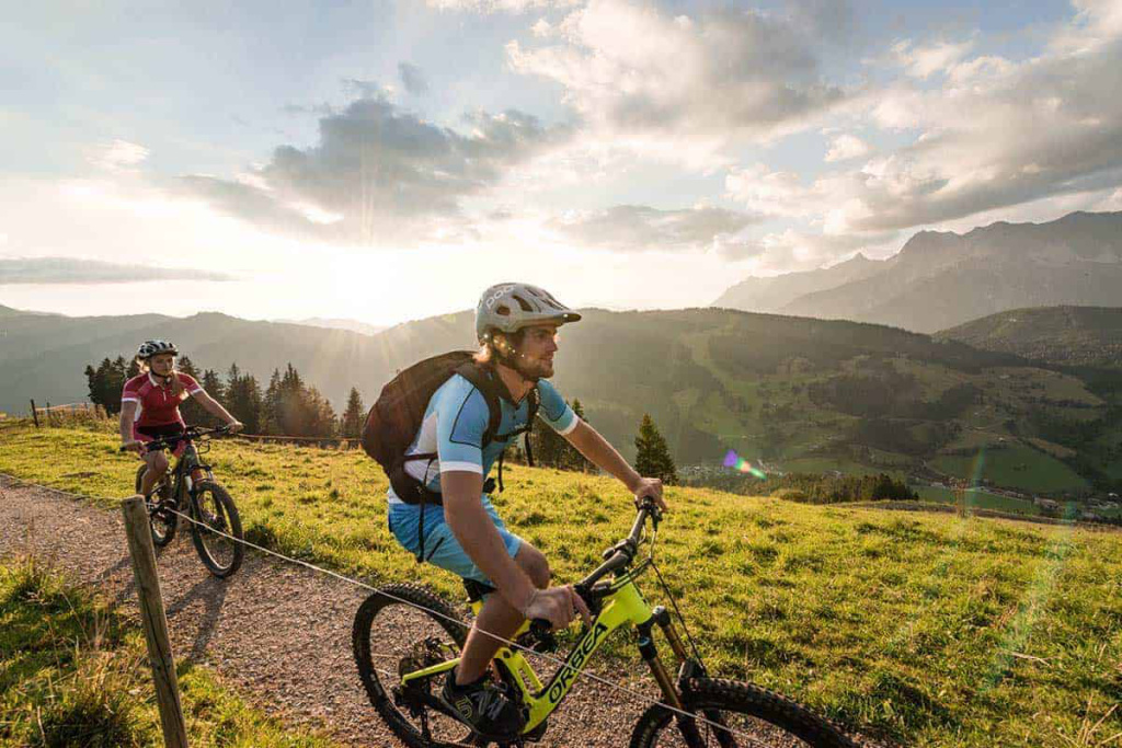 Mountainbiker genießen die Aussicht auf die Salzburger Alpen bei Sonnenuntergang.