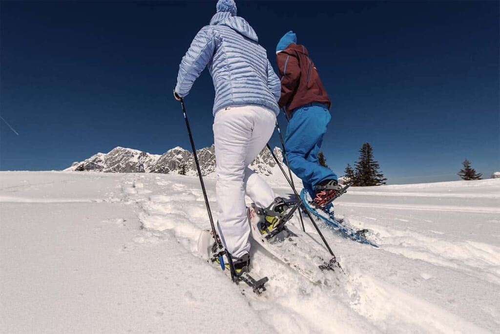 Skifahrer bei Sonnenlicht auf verschneiter Piste in den Salzburger Alpen, Hochkönig-Gebiet.