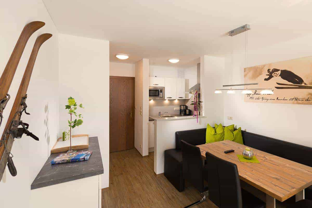 Moderne Küchenzeile mit Esstisch, Skiern und gemütlichem Wohnbereich im Apartmenthaus Rainer.
