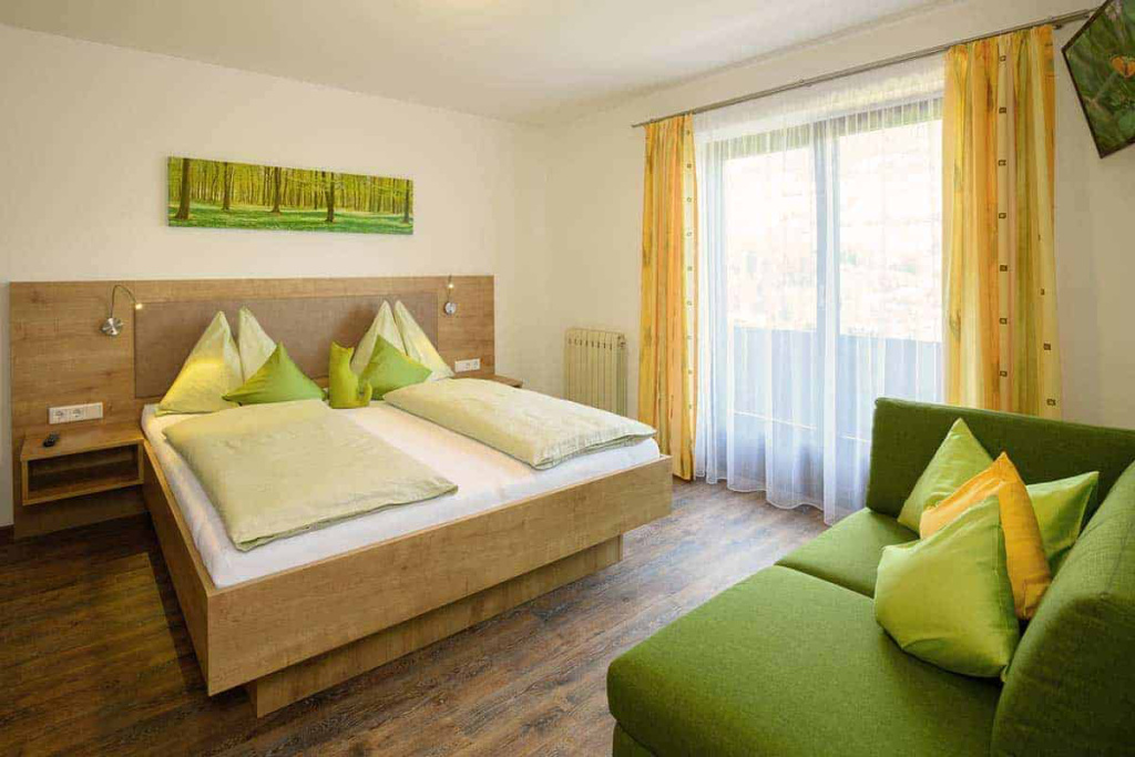 Gemütliches Schlafzimmer mit Doppelbett, grünen Akzenten und Balkon in Mühlbach am Hochkönig.