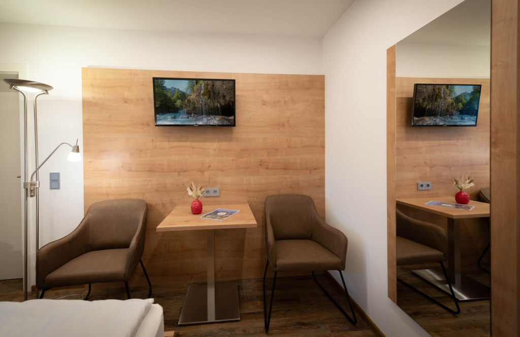Gemütliche Sitzecke mit Tisch, Fernseher und stilvollem Licht im Apartment Rainer.
