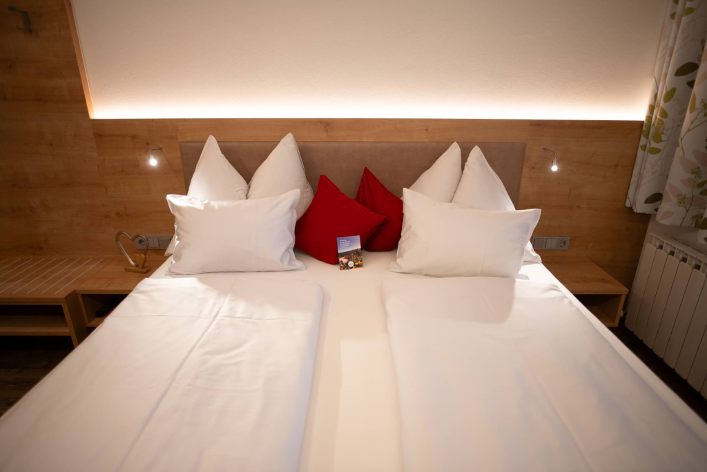 Gemütliches Schlafzimmer mit weißen und roten Kissen in modernem Holzdesign.