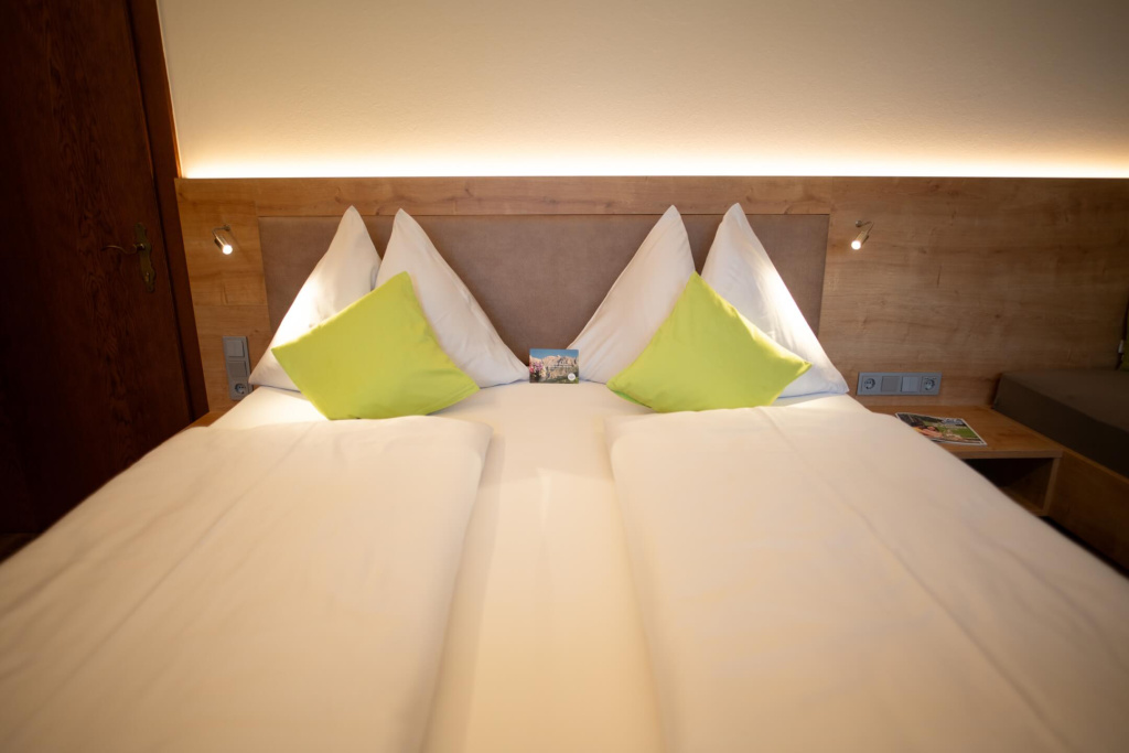 Gemütliches Doppelbett mit Kissen und sanfter Beleuchtung im Apartmenthaus Rainer.